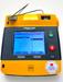 A Physio Control Lifepak 1000 AED defibrillator with a graphical/ECG display, orange casing, and a carrying case.